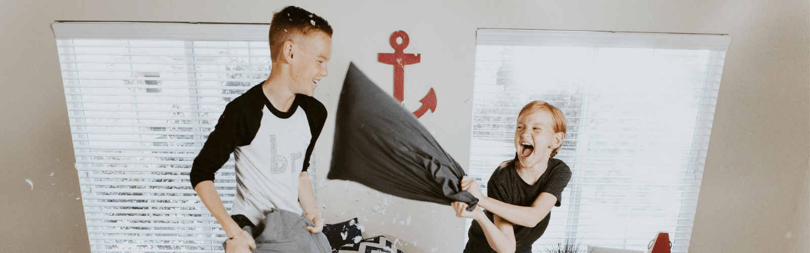 a young boy and girl having a pillow fight on a bed